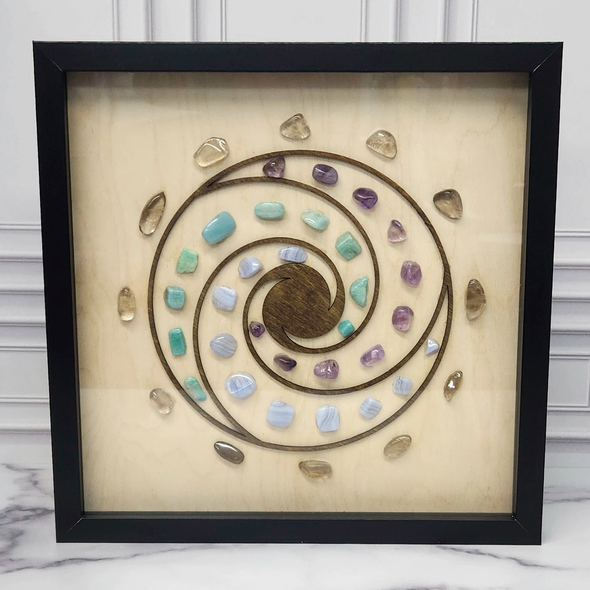 Calm and Peace crystal grid in a black glass-front shadow box, front view