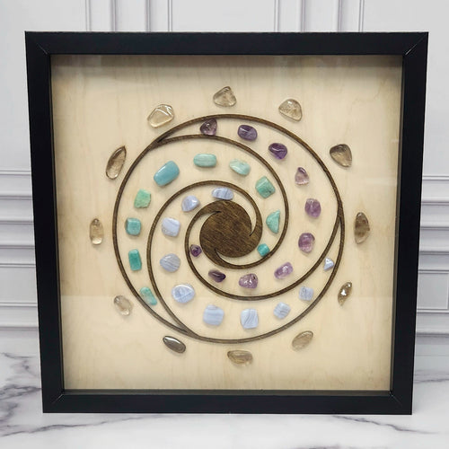 Calm and Peace crystal grid in a black glass-front shadow box, front view