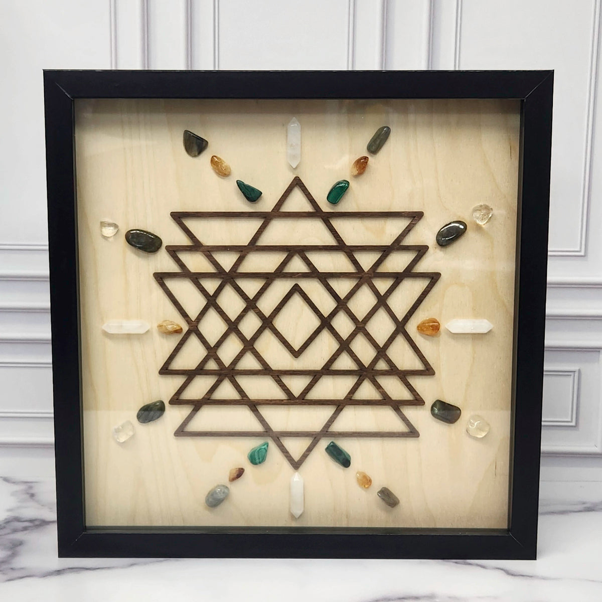Manifestation crystal grid in a black glass-front shadow box, front view
